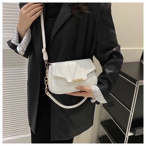 Close-up of a white leather flap bag with gold metal trim and chain strap on a black blazer