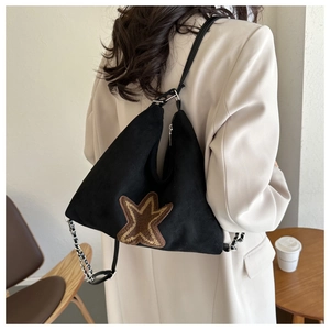 Details einer schwarzen matten Schultertasche mit braunem Wildlederstern und Silberkette