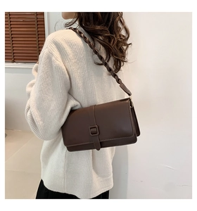 Dettaglio di una borsa a tracolla marrone scuro con spallina a treccia spessa e chic