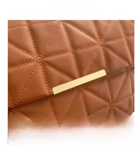 Détail macro du cuir matelassé marron et des finitions métalliques dorées du sac à main