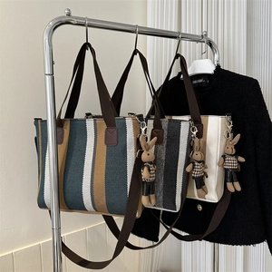 Three striped canvas tote bags with leather handles and cute bunny charms in a studio setting