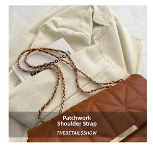 Détail d'un sac bandoulière matelassé marron sur un blazer blanc avec bandoulière chaîne