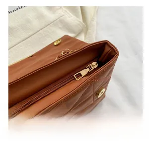 Détail de la fermeture éclair dorée lisse et du cuir matelassé marron du sac à main