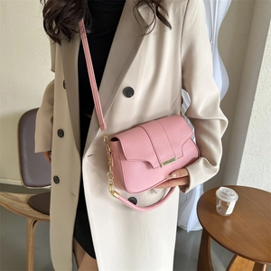 Chic pink matte leather crossbody bag with gold buckle on a model in a modern interior