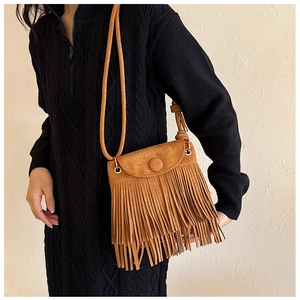 Gros plan d'un sac à bandoulière marron à franges porté avec un pull en maille noir