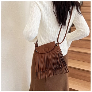 Détail du sac bandoulière en daim marron avec couches de franges et bouton en métal