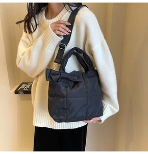 Close-up of black quilted down bag with large bow detail and detachable strap