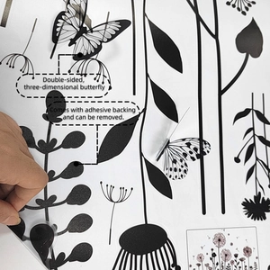 Detail of self-adhesive 3D black dandelion wall sticker being peeled off for removal