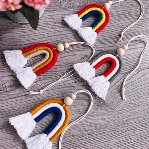 Détail de quatre mini arcs-en-ciel faits main avec glands en coton et perles en bois naturel