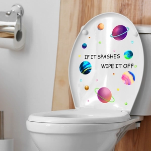 Luminous planet toilet stickers with stars and cleanup text on white lid in bathroom