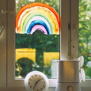 Rainbow window film decor with minimalist humidifier and analog clock on a bright windowsill