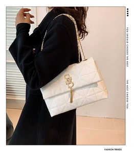 Détail du sac en cuir matelassé blanc avec boucle logo S dorée et pompon métallique