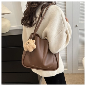 Sac fourre-tout marron en similicuir avec charme d'ours porté par un mannequin