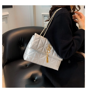 Sac bandoulière argenté matelassé avec logo S doré et chaîne sur un mannequin