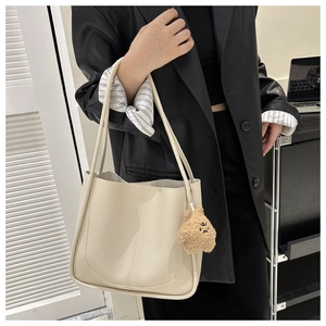 Detailed view of beige leather tote bag with a cute brown plush bear charm accessory