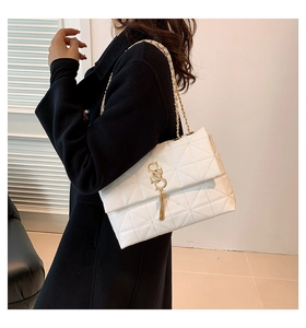Détail du sac matelassé blanc à chaîne avec breloque SS dorée et pompon chic
