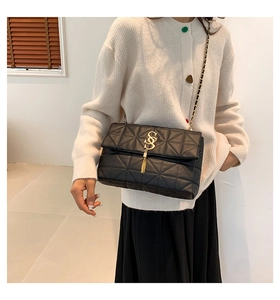 Détail d'un sac bandoulière noir matelassé avec boucle dorée SS, frange et chaîne métal