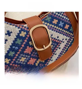 Detail of colorful woven geometric pattern on a handbag with brown leather trim and gold buckle