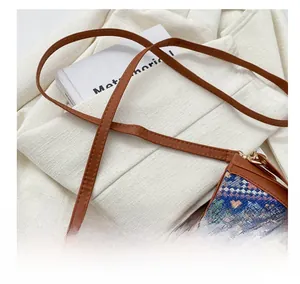 Detail of adjustable leather strap and gold hardware on ethnic style woven crossbody bag