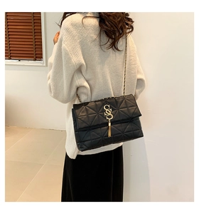Détail du sac à bandoulière matelassé noir avec logo SS doré, pompon et chaîne pour femme