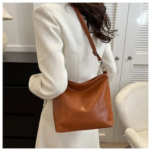Détail du sac seau en similicuir caramel montrant la texture souple et le crochet en métal