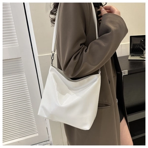 Gros plan d'un sac seau blanc minimaliste en cuir PU avec bandoulière et boucles noires