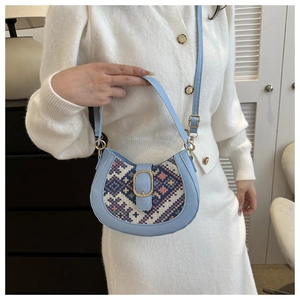 Close-up of light blue crescent bag with ethnic fabric detail on a model
