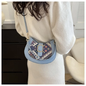 Detail of light blue saddle bag featuring bohemian woven pattern and gold metal buckle