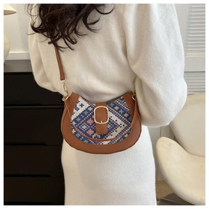 Brown half-moon crossbody bag featuring ethnic geometric patterns worn on the shoulder