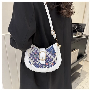 Detail of white saddle bag with colorful geometric woven pattern and gold metal buckle