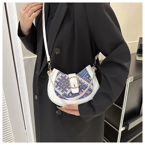 White crescent saddle bag featuring ethnic embroidery on a model in a black wool coat