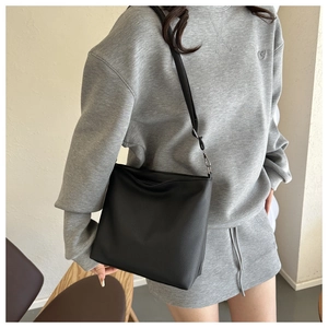 Detailed shot of black lychee grain leather crossbody bucket bag with adjustable strap