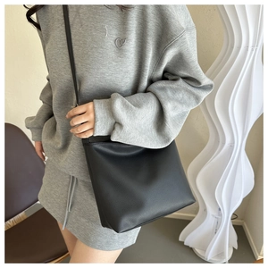 Detail of black lychee grain leather bucket bag shown on model in a modern casual style