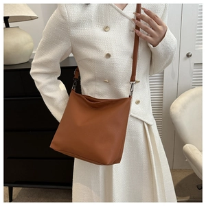 Detail of brown pebbled leather bucket bag with slim shoulder strap and metal hardware