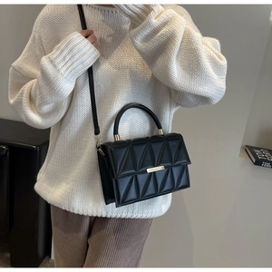 Close-up of black quilted crossbody bag with gold hardware and curved handle for women