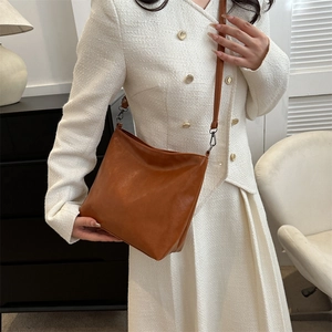 Sac seau chic en cuir marron pour femme présenté dans un intérieur moderne élégant