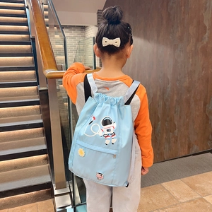 Child wearing light blue nylon drawstring backpack featuring cartoon astronaut pattern