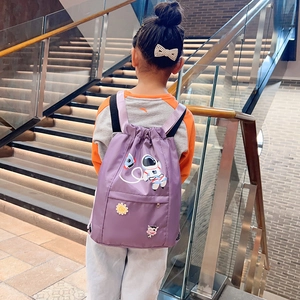 Rear view of a child carrying a purple nylon drawstring backpack with cartoon patches