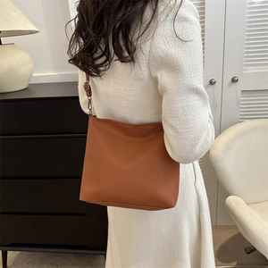 Brown litchi grain leather tote bag worn by a model in a minimalist setting