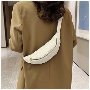 Rear view of model wearing a white fuzzy sherpa belt bag with khaki blazer outfit
