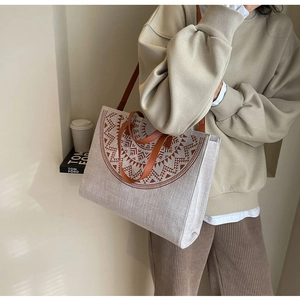 Detail view of canvas tote bag with geometric print and brown leather shoulder strap