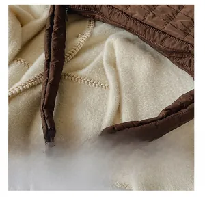 Detail showing the brown quilted shoulder bag with its wide padded strap and metal zipper