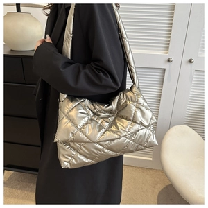 Quilted puffer shoulder bag with metallic finish shown on model in modern room
