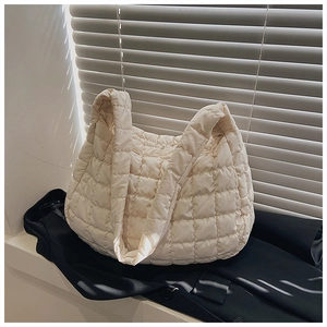 Macro shot of quilted cloud tote bag with grid texture on a black suit by a window