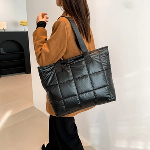 Fashionable black quilted puffer tote bag in glossy nylon shown in a model lifestyle view