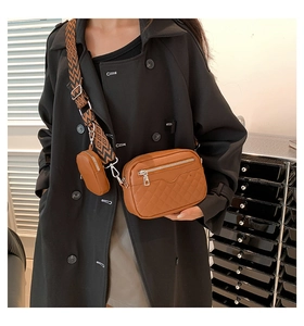 Close-up of brown quilted crossbody bag with stylish patterned wide shoulder strap