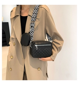 Detail of black quilted crossbody bag with patterned strap and mini round coin pouch