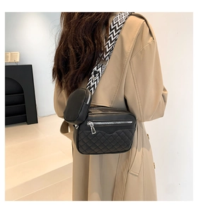 Detail of black quilted crossbody bag with dual zippers and geometric wide strap