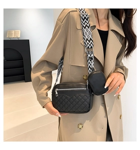 Detail of black quilted crossbody bag with wide geometric strap and coin purse