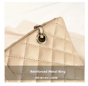 Detail of beige quilted bag with reinforced metal ring and dark gunmetal chain strap